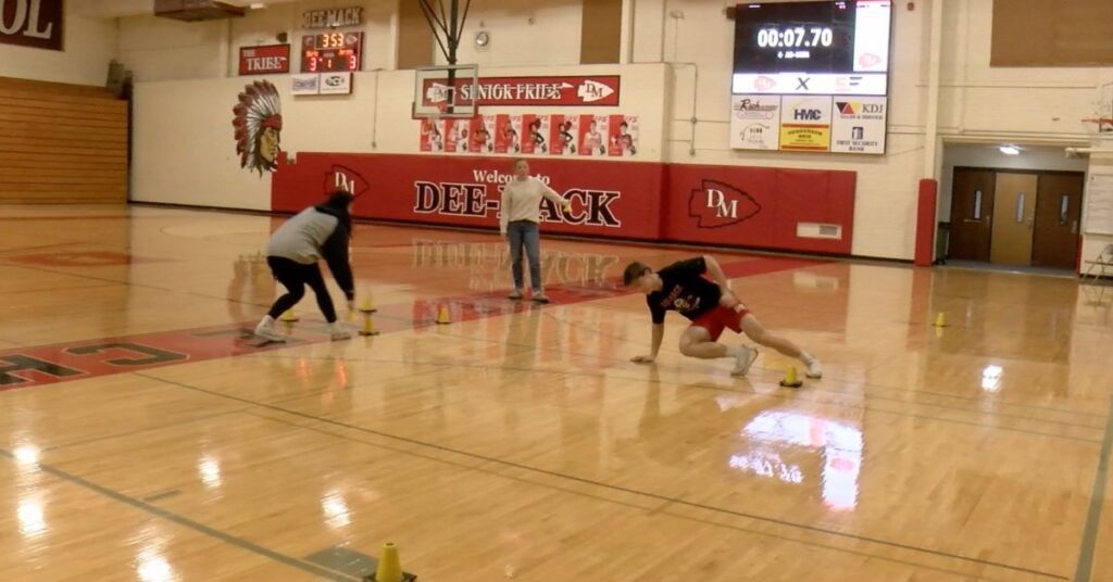 Athlete runs agility drill timed with the Freelap system with the results projects on the high school gym scoreboard.