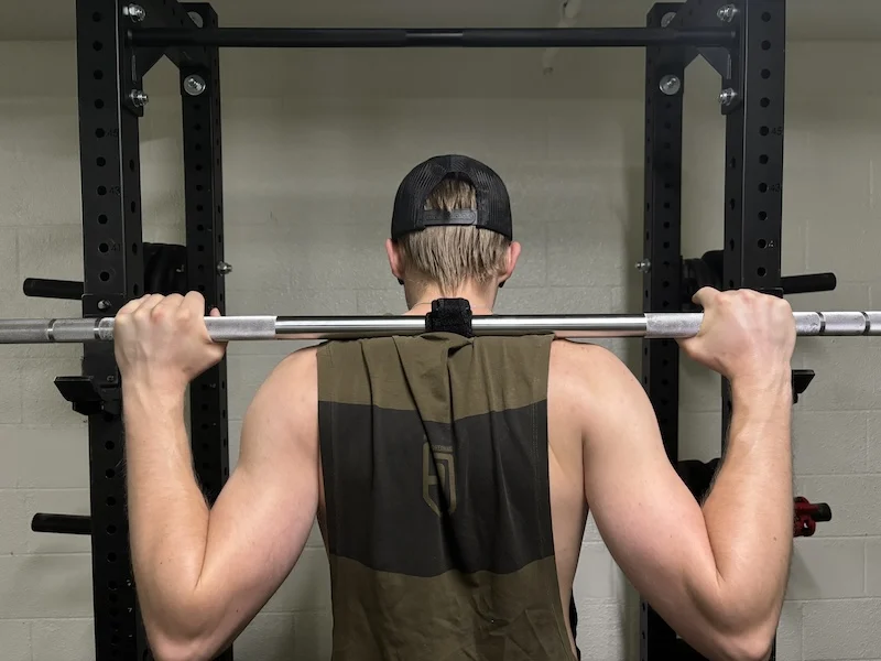 An athlete using the Enode sensor on the barbell during squats.