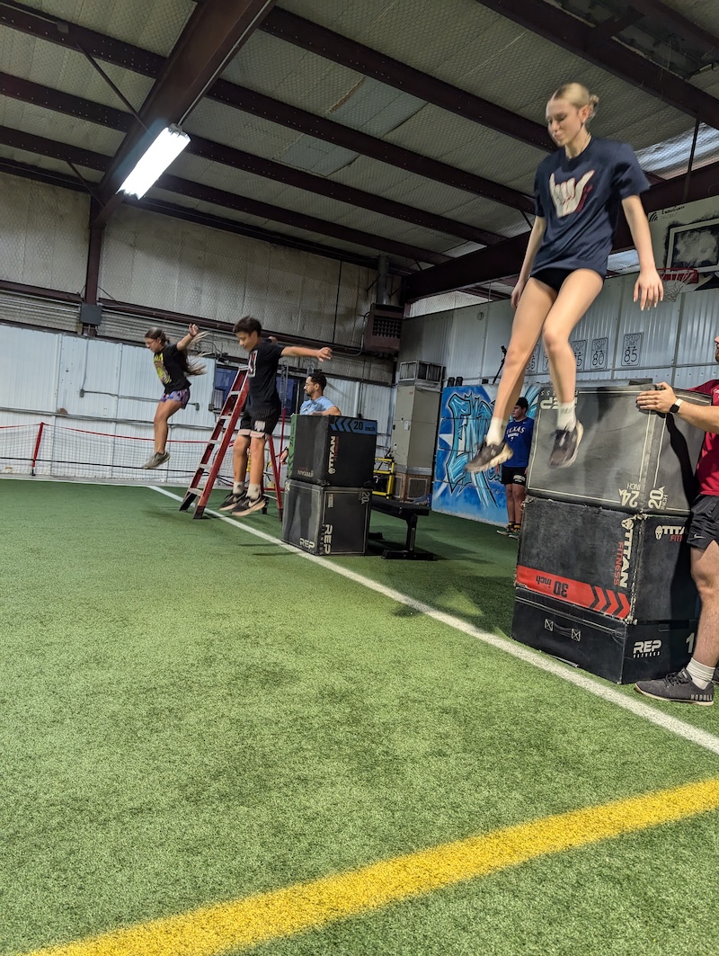 High school female athlete performs depth drop to train deceleration.