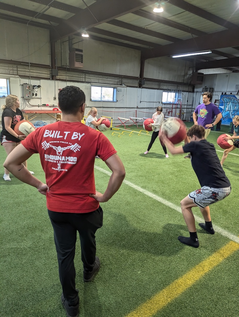 Athletes at training facility use medball pulldown throws to train in a low stress manner.
