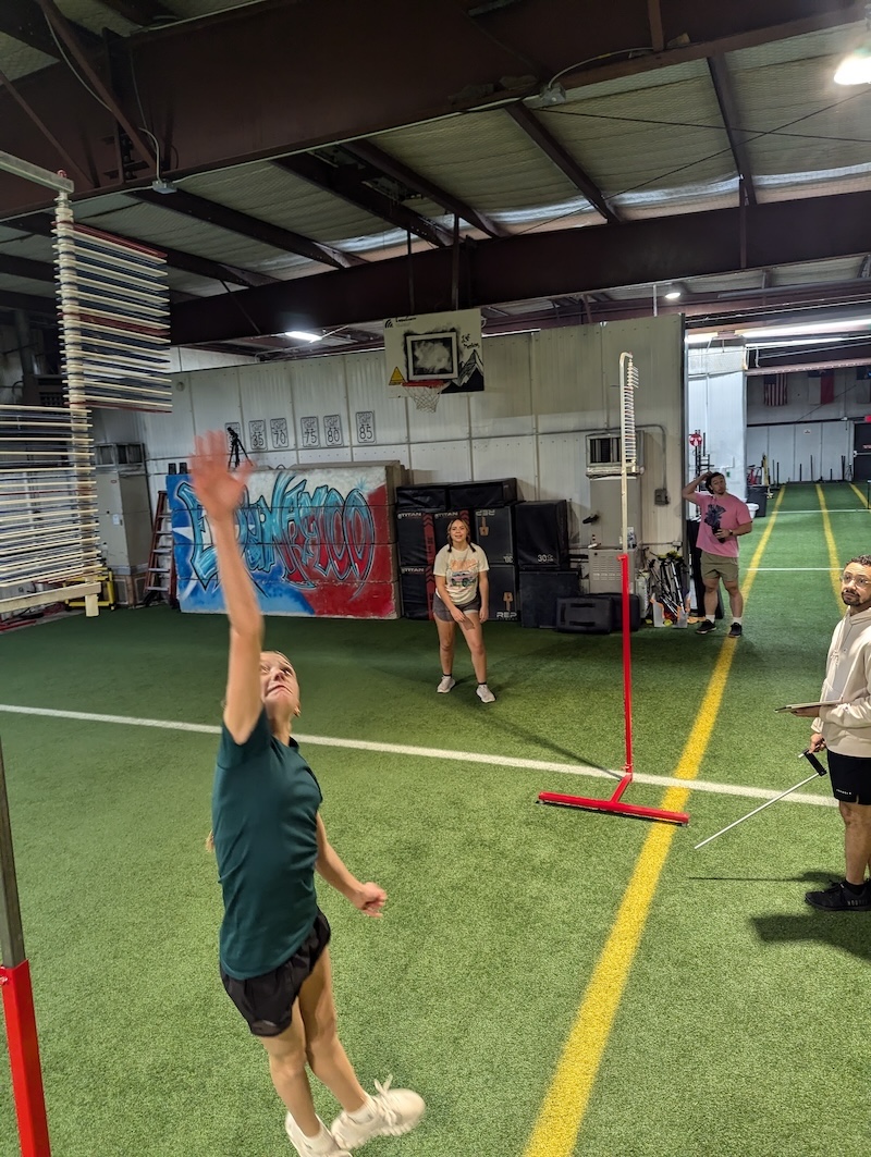 Athletes in training perform running vertical jump with Vertec testing system.