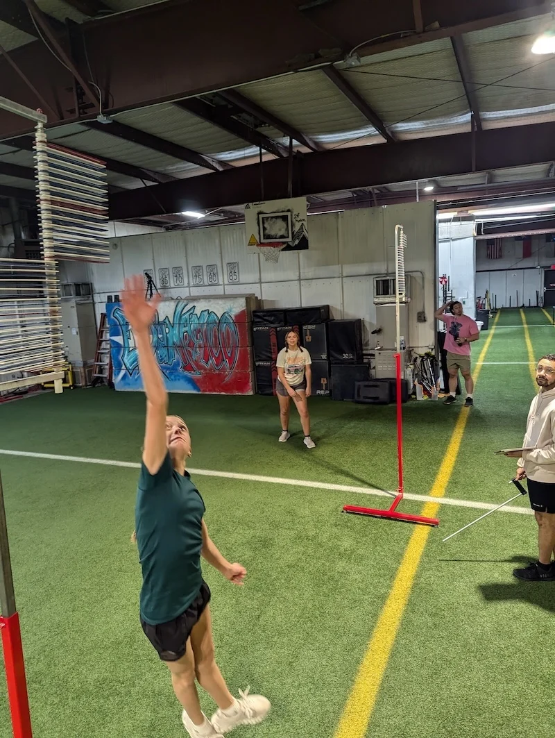 Athletes in training perform running vertical jump with Vertec testing system.