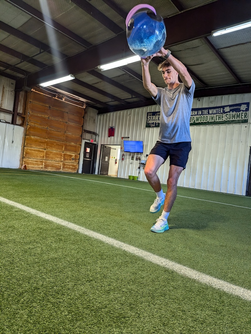 Balancing on one leg, athlete performs swing exercise with a water-based weight system.