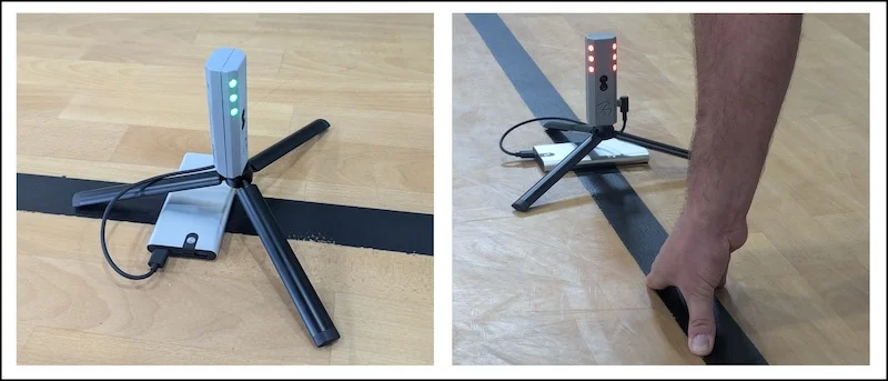 A small tripod-mounted electronic device with red and green lights is on a wooden floor. In the second image, a person is adjusting or using the device next to a black line on the floor.