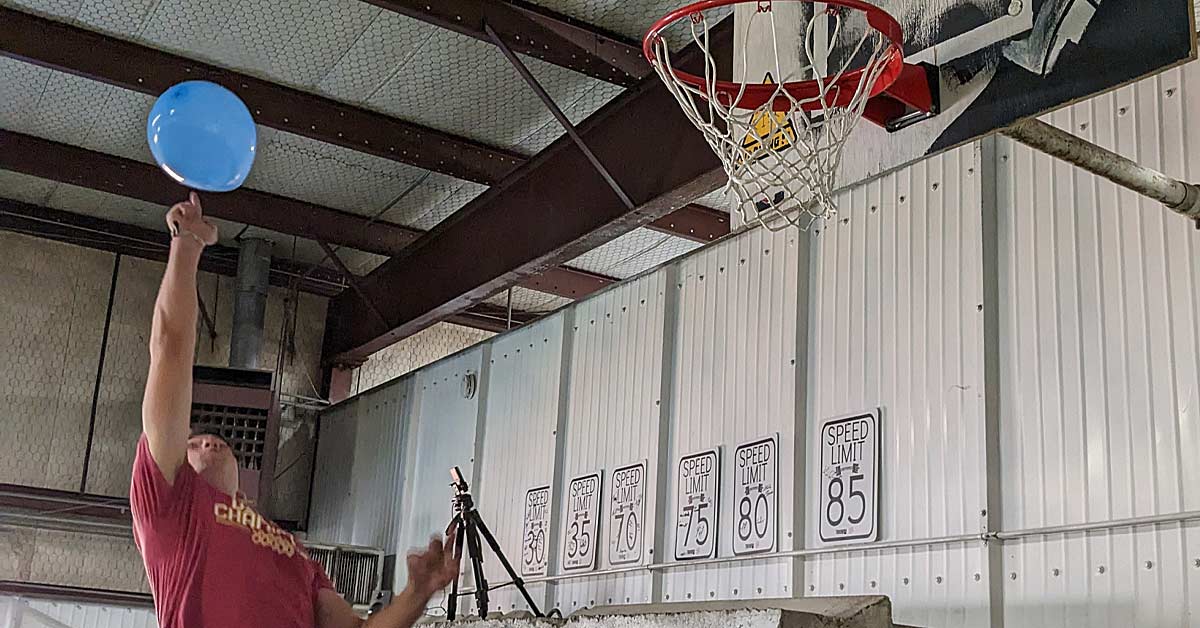 Balloon Training|A person running indoors while holding a large blue balloon with a logo. Other people and gym equipment are visible in the background. The text on the image reads
