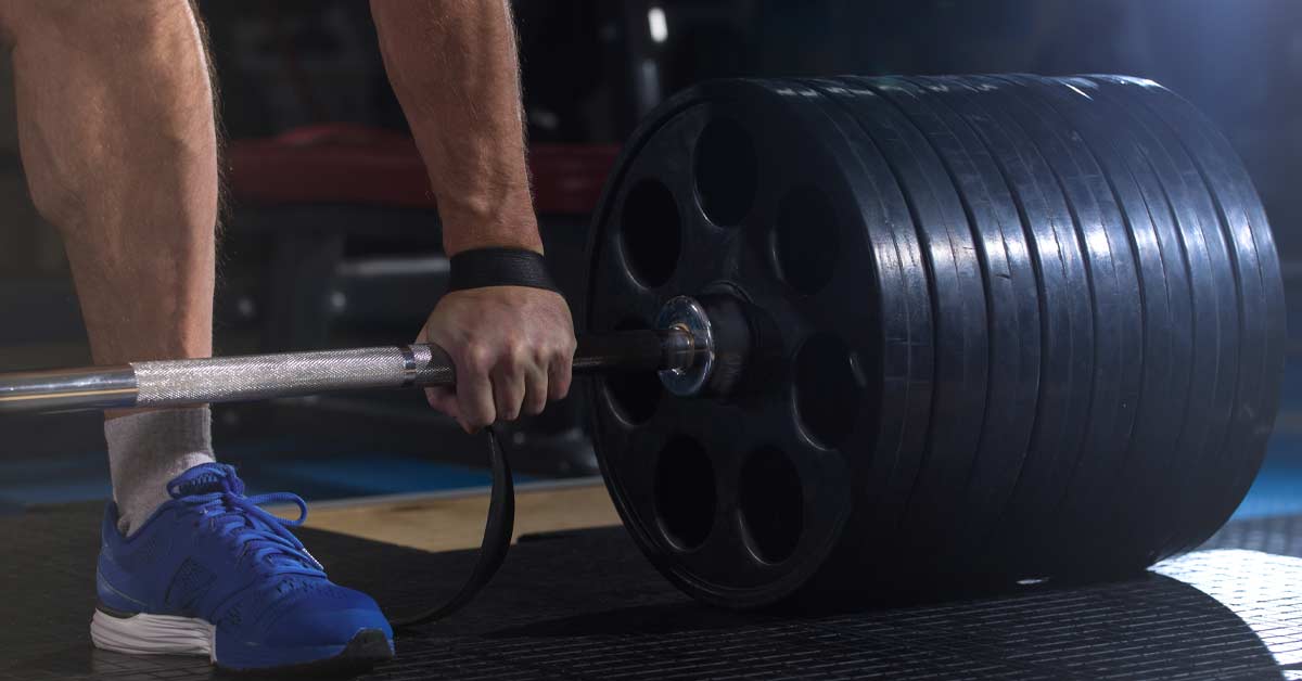 Eccentric Training GymAware|GymAware-App|Force-Velocity|GymAware|Flex App|A person performing a snatch lift with a barbell in a dimly lit gym. A digital display shows a timer