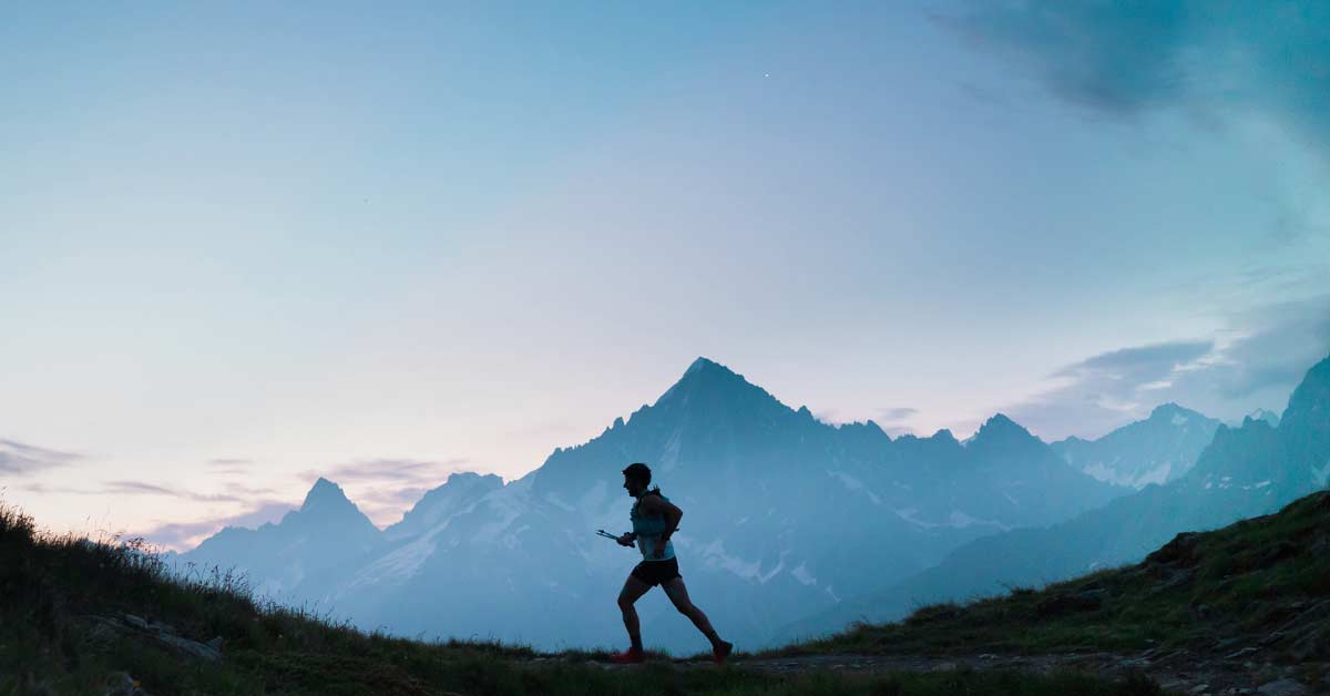 Training at elevation|A person is running on a mountain trail at dawn