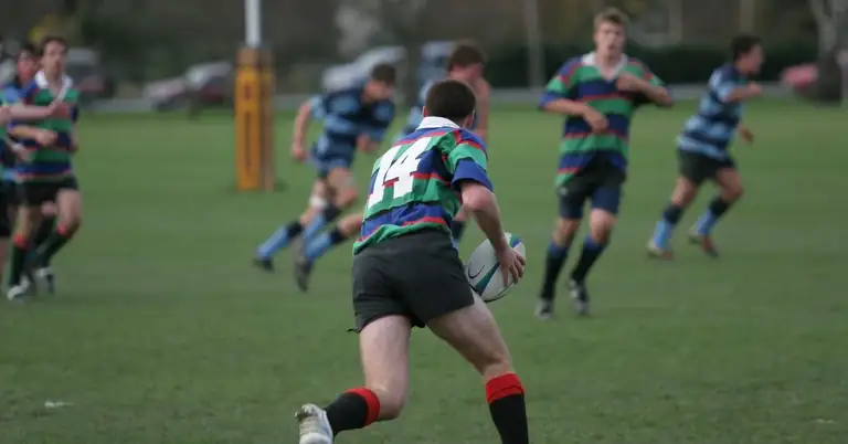 Rugby Specialization|A group of young men in black and yellow sports jerseys gather around a table with snacks. One person humorously wears a cardboard box on their head. The room has trophy plaques on the walls.|Paralympic Athlete