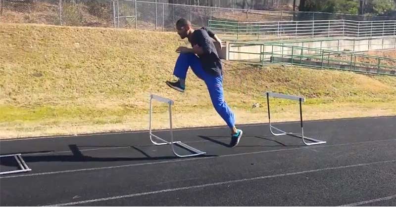 Hurdler Hector Cotto|A person in blue pants and a black shirt is standing on a track