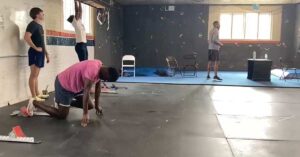 Four people in a gym. One person is kneeling on the ground