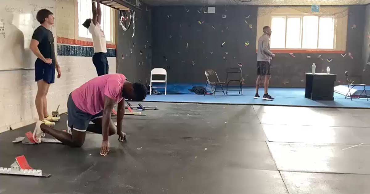 Four people in a gym. One person is kneeling on the ground