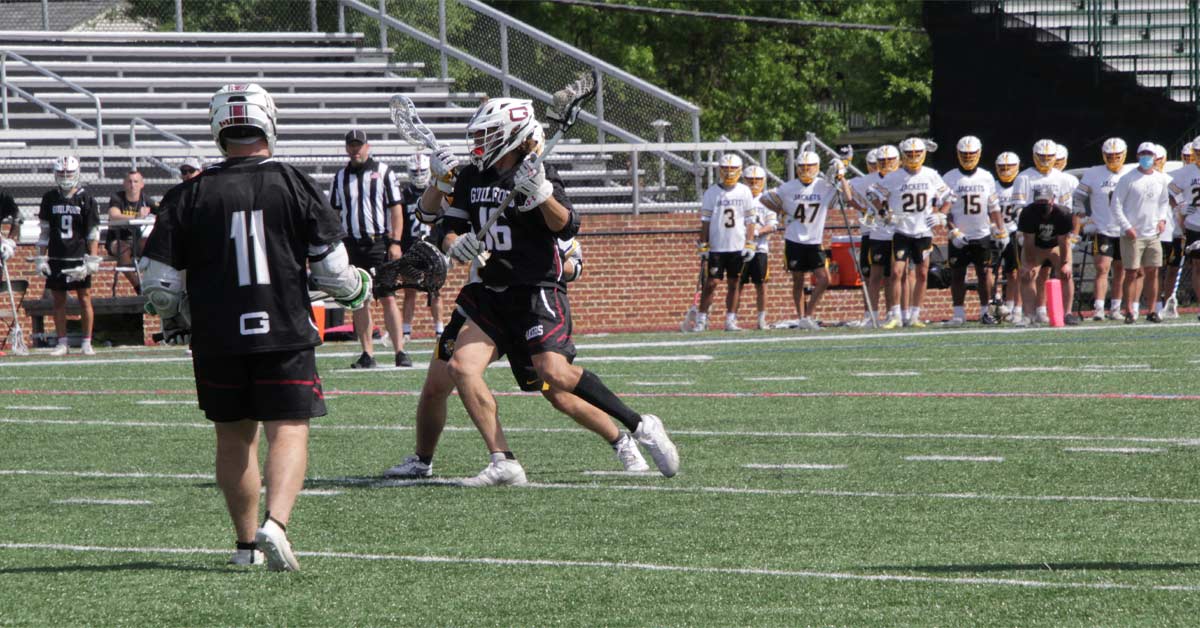 Lacrosse FTC|Two men playing indoor lacrosse on a turf field. One is trying to evade the others defense