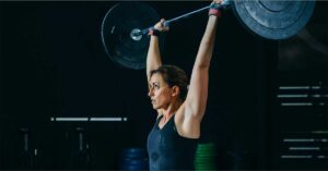Overhead Lifting|LTAD Vermeil Chart|Rotator Cuff|Acromion|Pressing Overhead|Arc|A woman in athletic wear is performing a front squat with a barbell in a gym. She has a focused expression