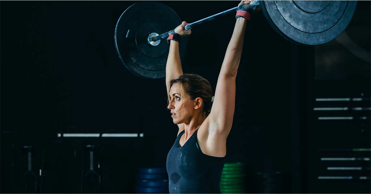 Overhead Lifting|LTAD Vermeil Chart|Rotator Cuff|Acromion|Pressing Overhead|Arc|A woman in athletic wear is performing a front squat with a barbell in a gym. She has a focused expression