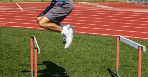 A person in athletic shorts and a blue shirt is seen mid-air