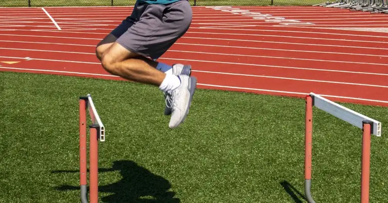 A person in athletic shorts and a blue shirt is seen mid-air