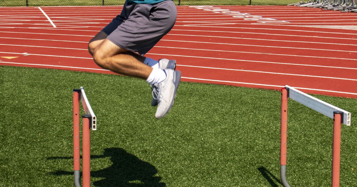 A person in athletic shorts and a blue shirt is seen mid-air