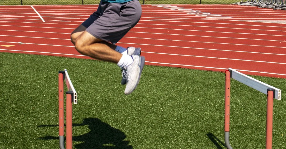 A person in athletic shorts and a blue shirt is seen mid-air