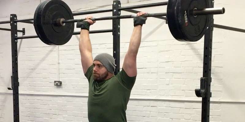 Overhead Press|Timeless Pressing|Overhead Press Periodization|A person lifting a barbell with weights in a gym