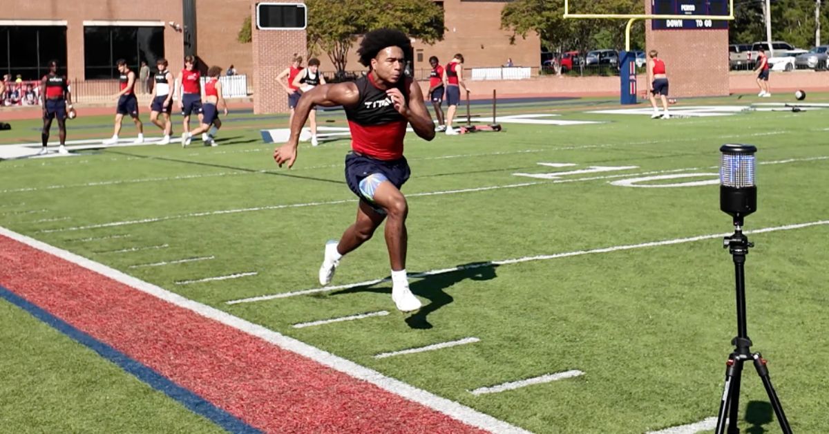High school athlete performs timed sprints as a way to break through a speed training plateau.|A blurred runner in sportswear speeds past a digital timer on a tripod