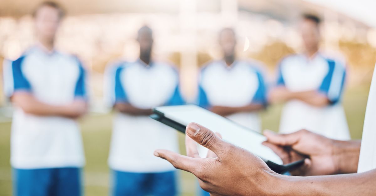 A coach holds a tablet on a soccer field