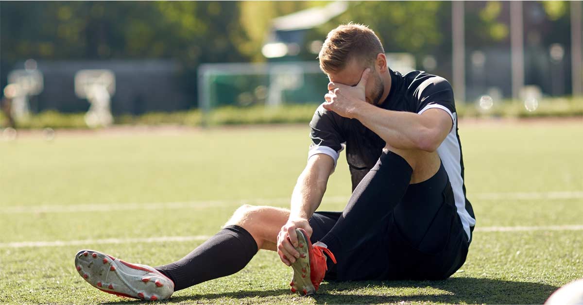 A soccer player sits on the field