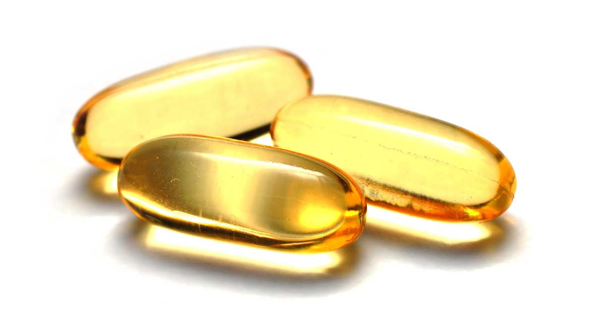 Three translucent yellow capsules are clustered together against a white background. The capsules are smooth and reflective