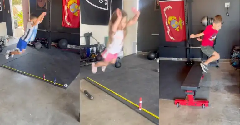 Three young children take turns jumping over a small hurdle indoors